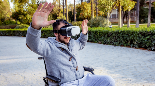man in a wheelchair with his hands in the air wearing a vr headset