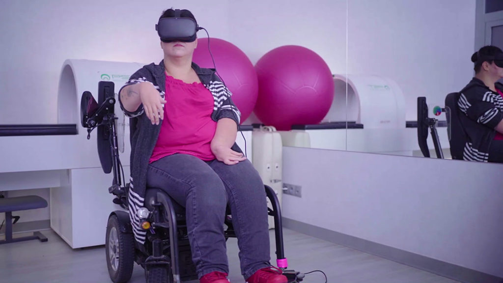 image of a woman in a wheelchair using a vr headset with her arm outstretched 