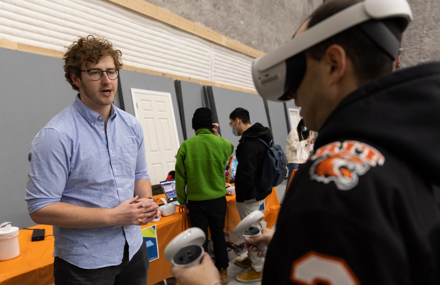 People at Rochester Institute of Technology's Frameless XR Symposium. Shows a student talking to a person in VR. 